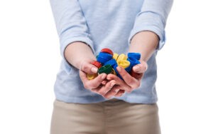 Pessoa estendendo as mãos, segurando várias tampas de garrafas coloridas