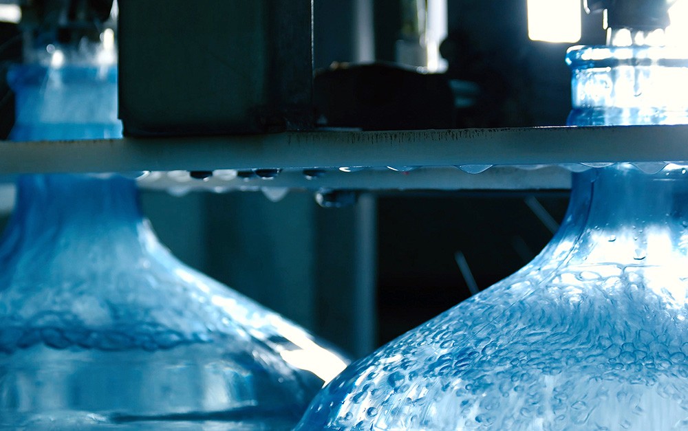 Envase de água mineral sendo feito em dois galões em uma empresa de distribuição de água